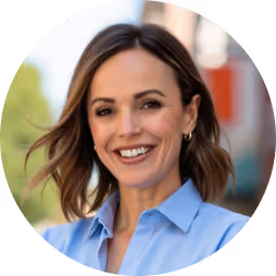 Smiling woman with shoulder-length brown hair wearing a blue collared shirt outdoors.