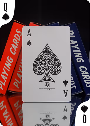 Red and blue Charminar tuck boxes placed side by side with the Ace of Spades in the center, positioned on a mirror surface reflecting the deck’s elegant design and intricate detailing.
