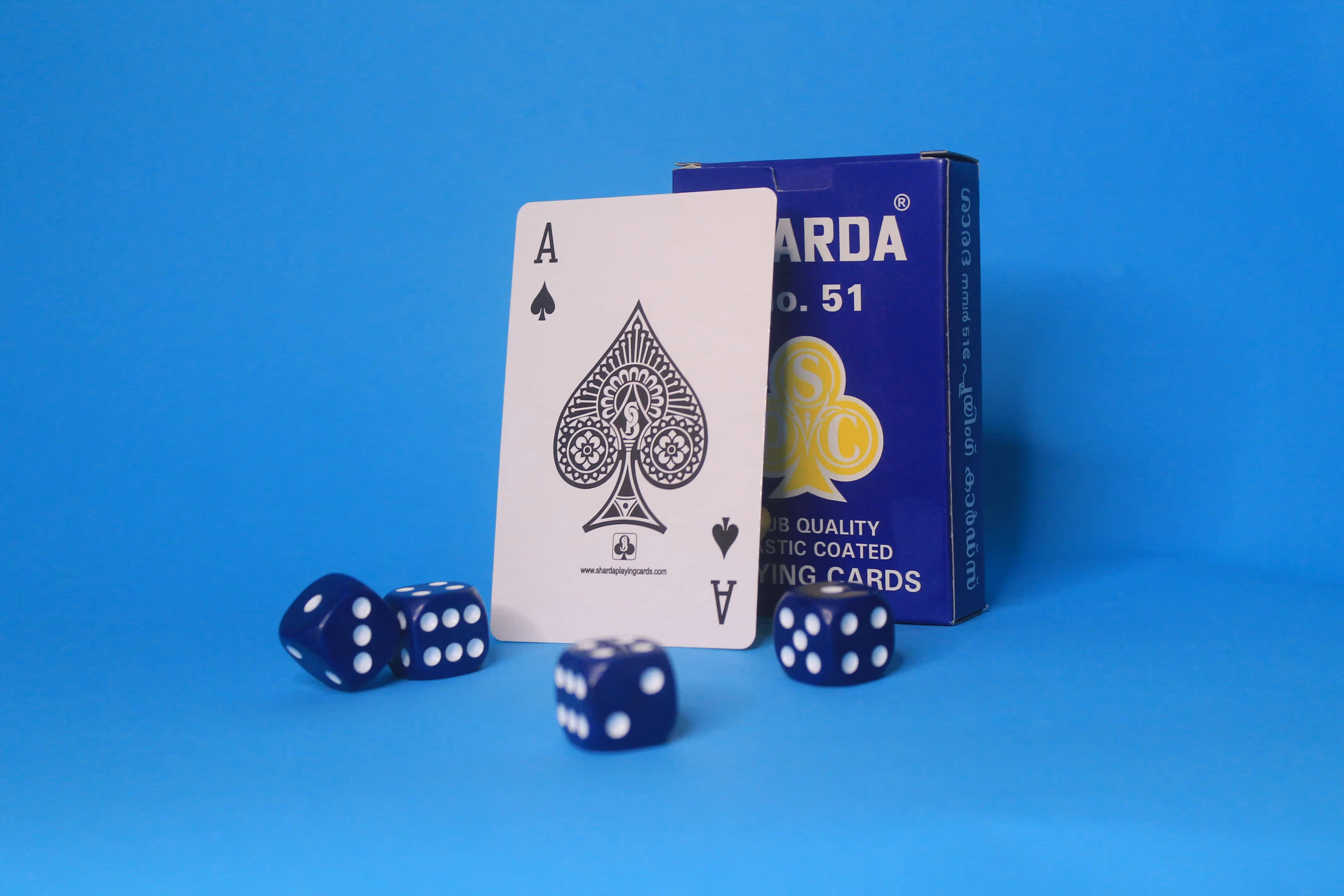 Blue Sharda No. 51 tuck box and matching card back displayed against a blue background, surrounded by scattered dice.”