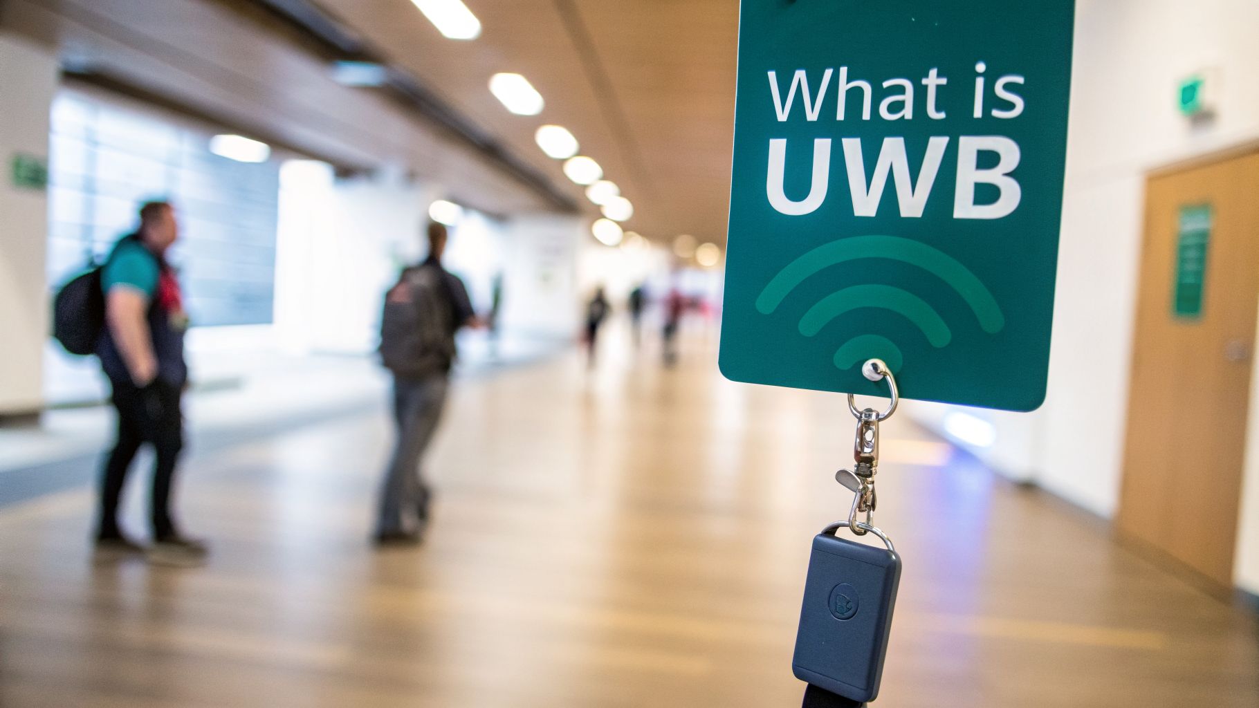 A green badge saying 'What is UWB' with a signal icon, in a blurred hallway with people.