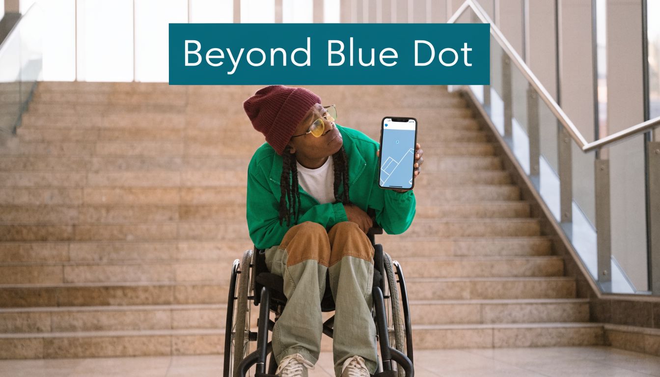 A person in a wheelchair holding a smartphone displaying an indoor map in a public building.