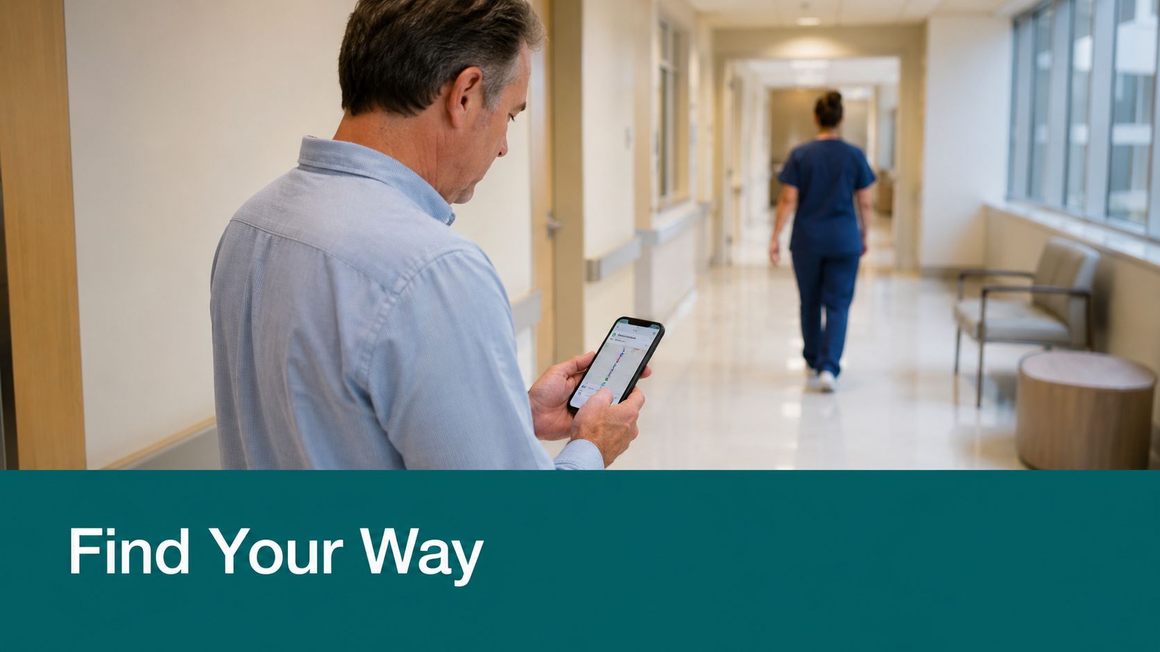 A man looking at a wayfinding app on his phone in a bright hospital corridor.