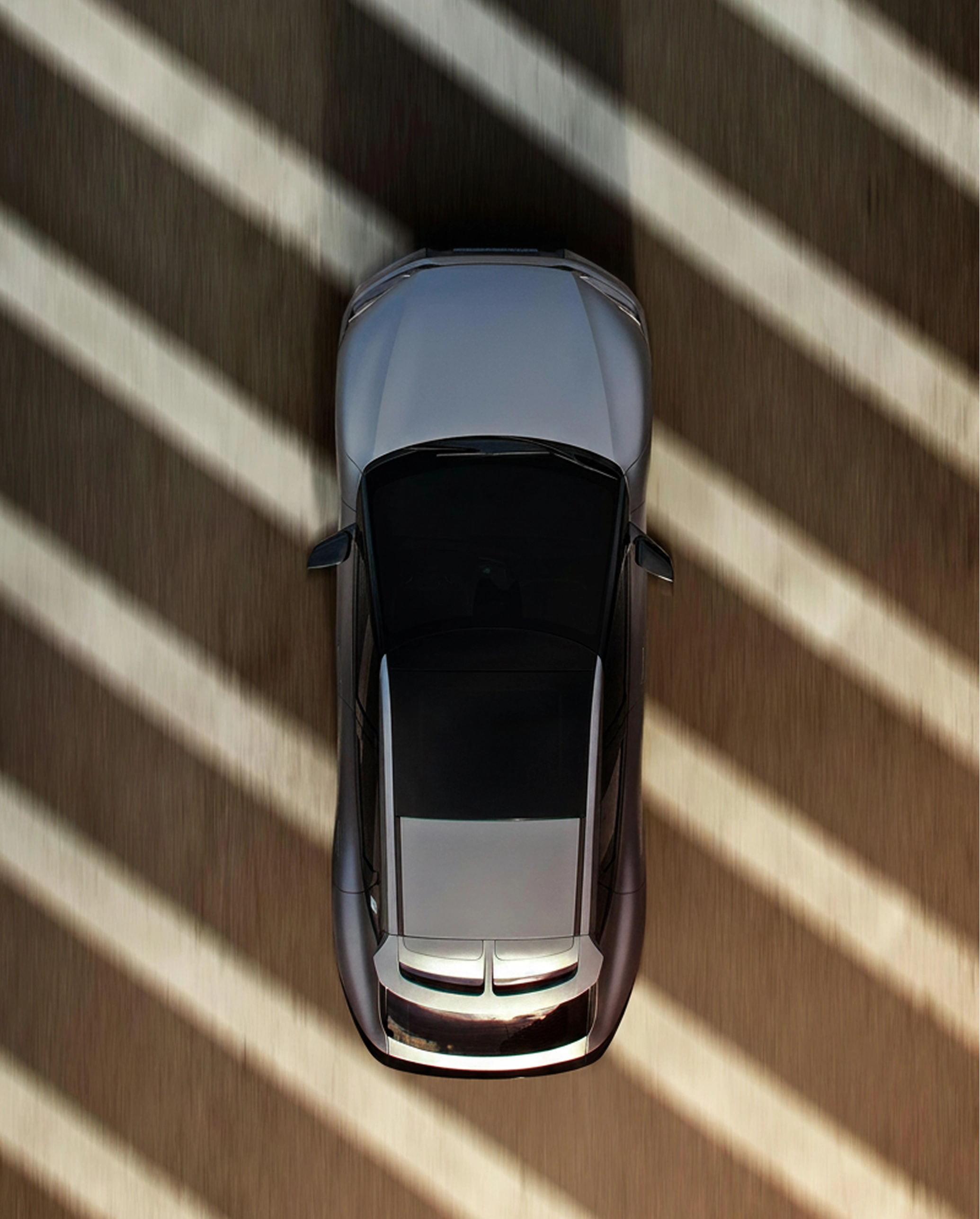 A silver electric car viewed from above with shadow stripes on the ground around it.