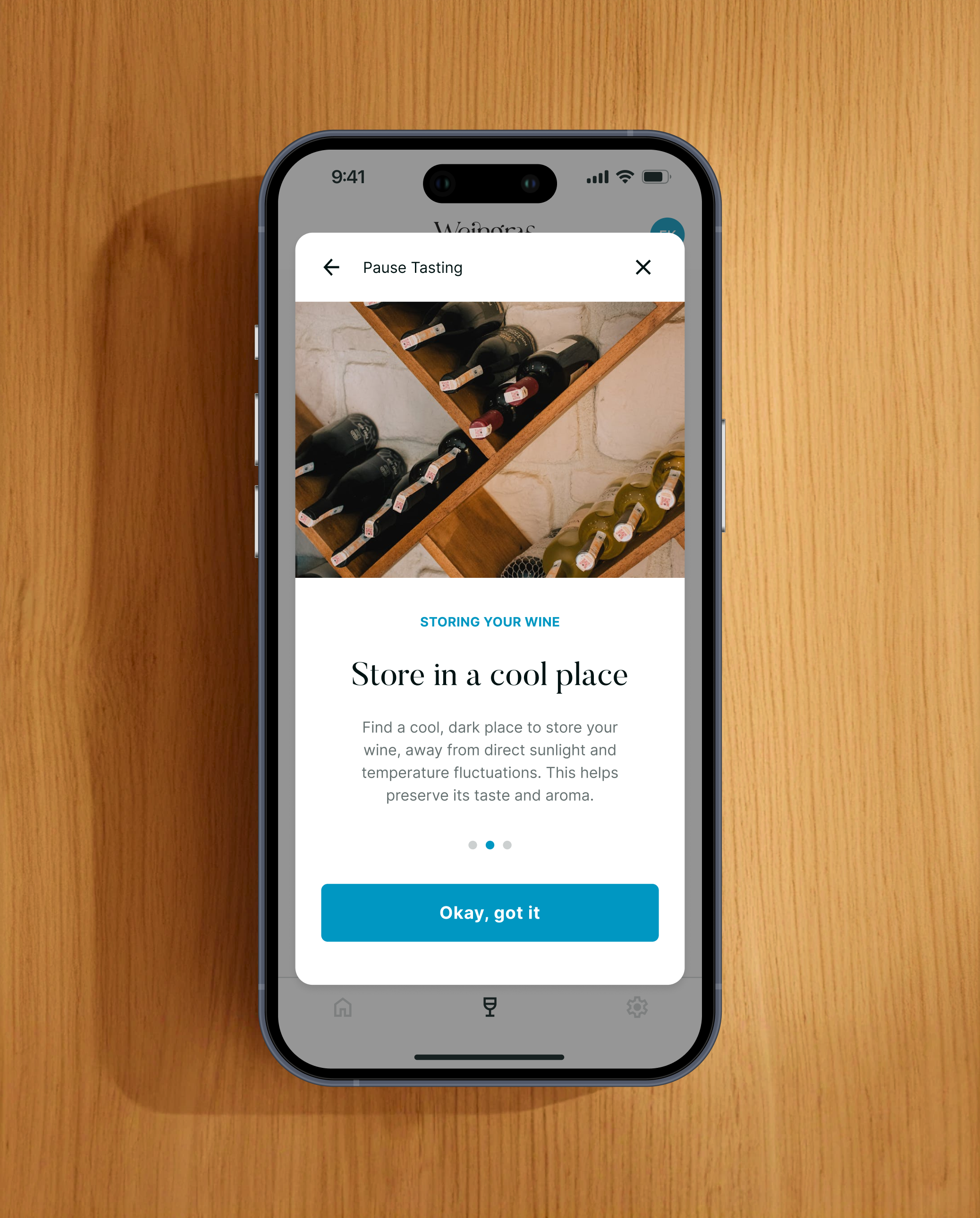 Smartphone-Mockup vor Holzuntergrund mit einem Dialog zum Pausieren der Weinverkostung. Die Benutzeroberfläche weist darauf hin, den Wein während der Pause richtig zu lagern.