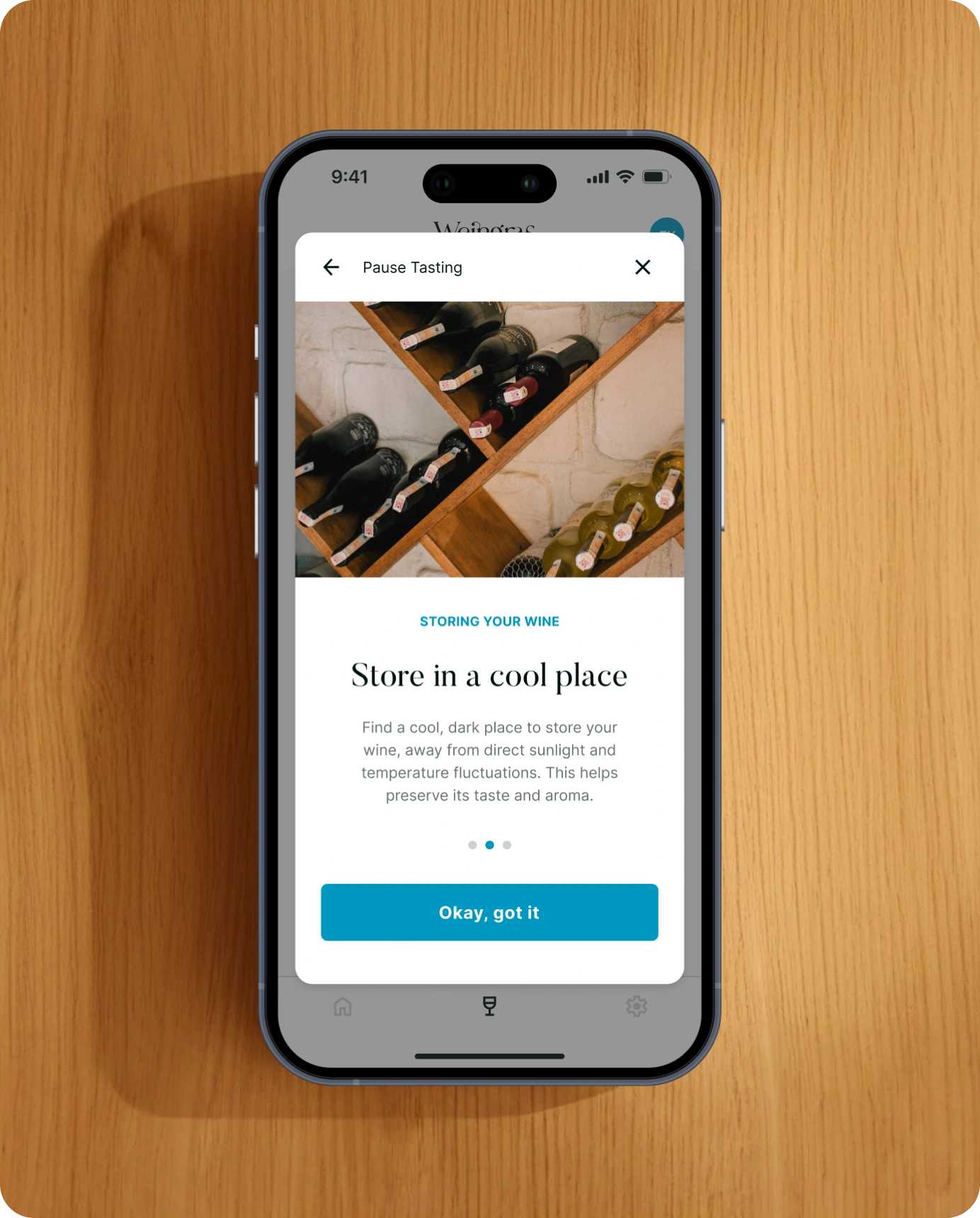 Smartphone-Mockup vor Holzuntergrund mit einem Dialog zum Pausieren der Weinverkostung. Die Benutzeroberfläche weist darauf hin, den Wein während der Pause richtig zu lagern.