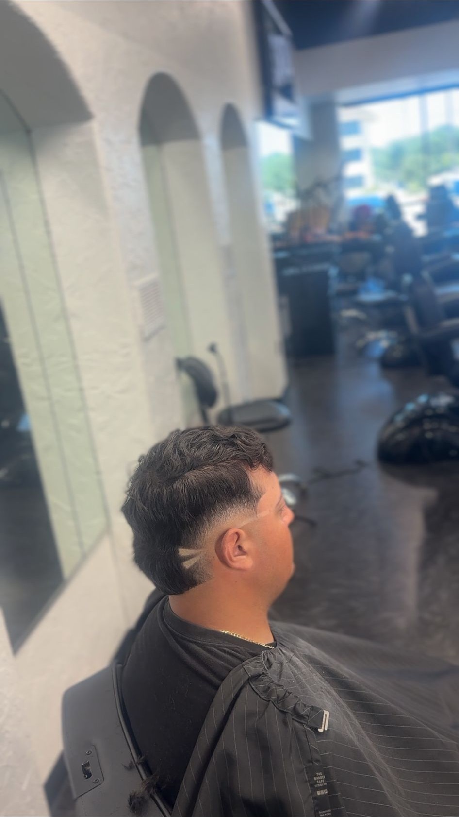 Skin fade with a curly top by a Santana Studio Co barber