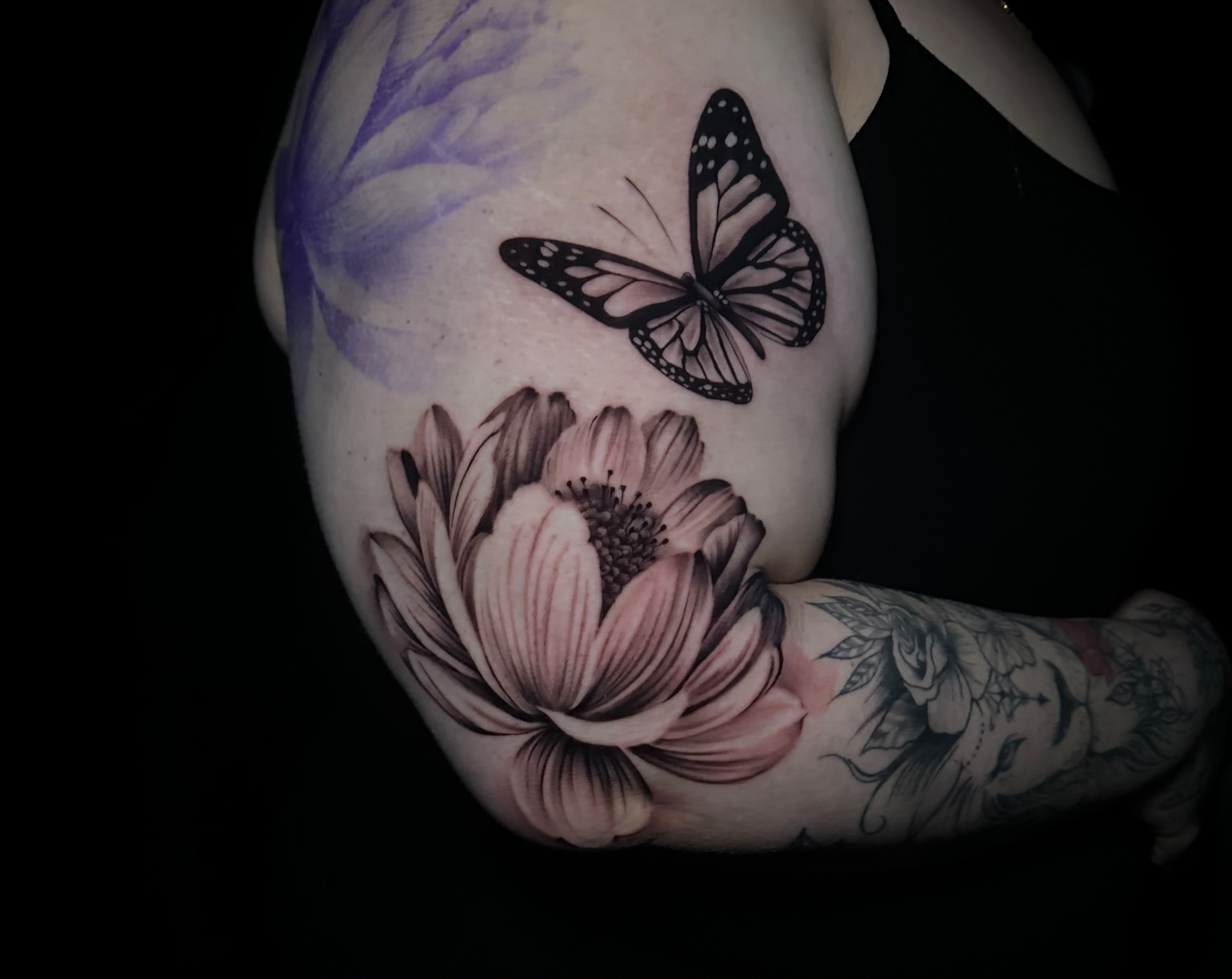 Black and grey butterfly and flower tattoo on upper arm by Dani B at Santana Studio Co, Fort Worth