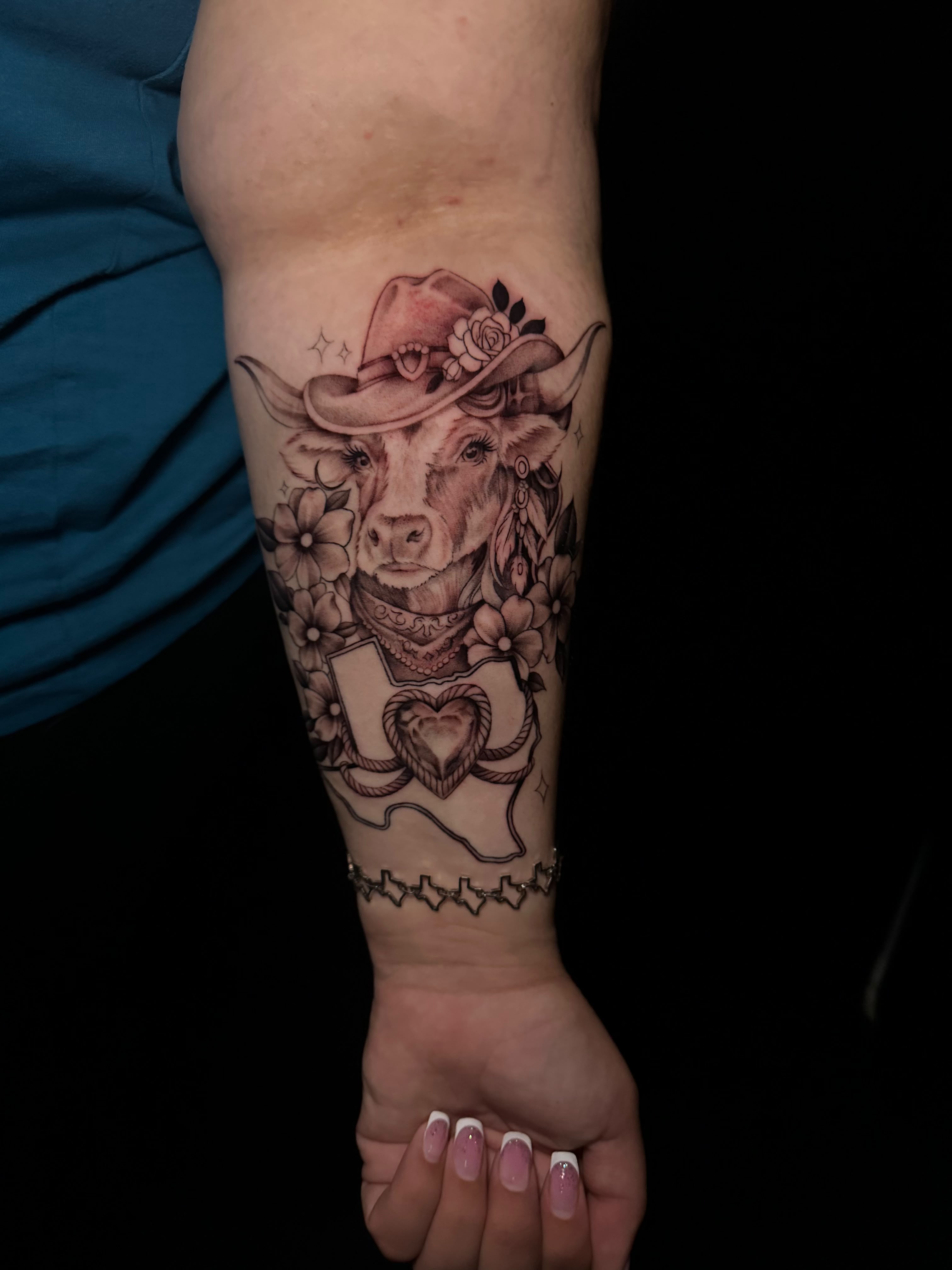 Texas longhorn cow with cowboy hat and flowers forearm tattoo by Dani B at Santana Studio Co