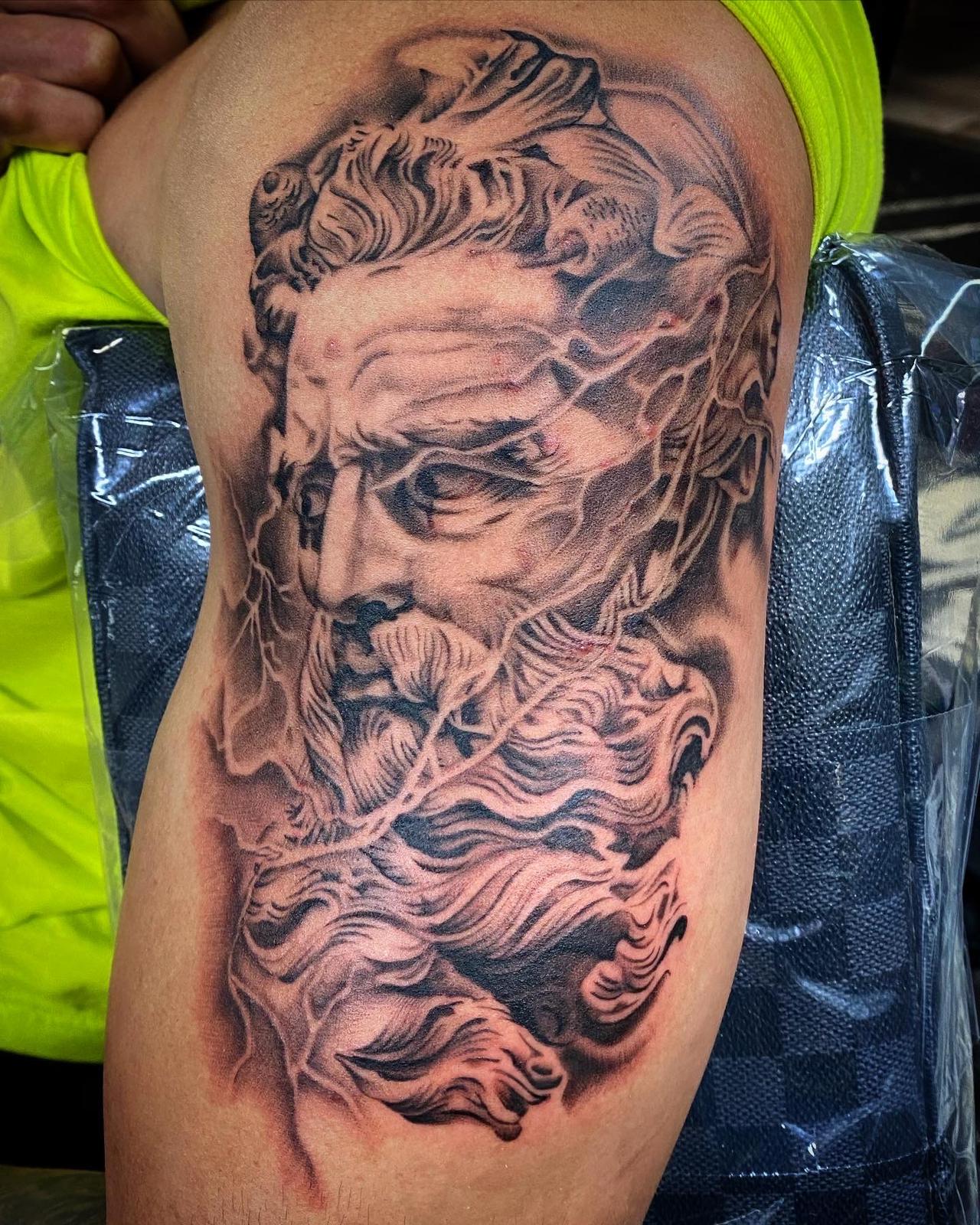 Black and grey Poseidon statue tattoo with waves and lightning on the upper arm by RESN at Santana Studio Co, Fort Worth
