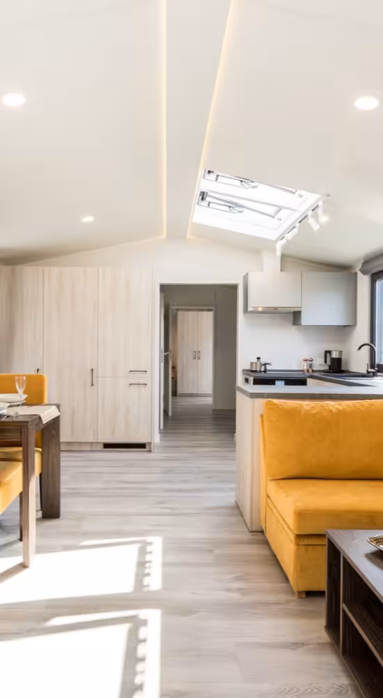 Licht interieur met gele sofa, open keuken en doorgang naar de slaapkamers