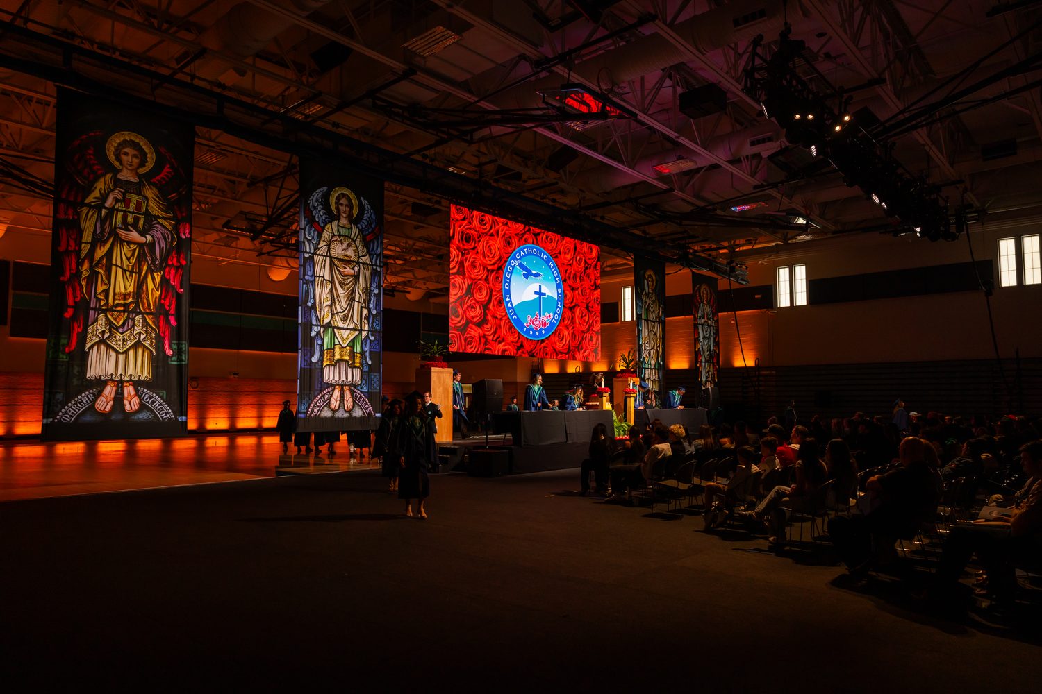 Juan Diego graduates processing past stained-glass banners during commencement