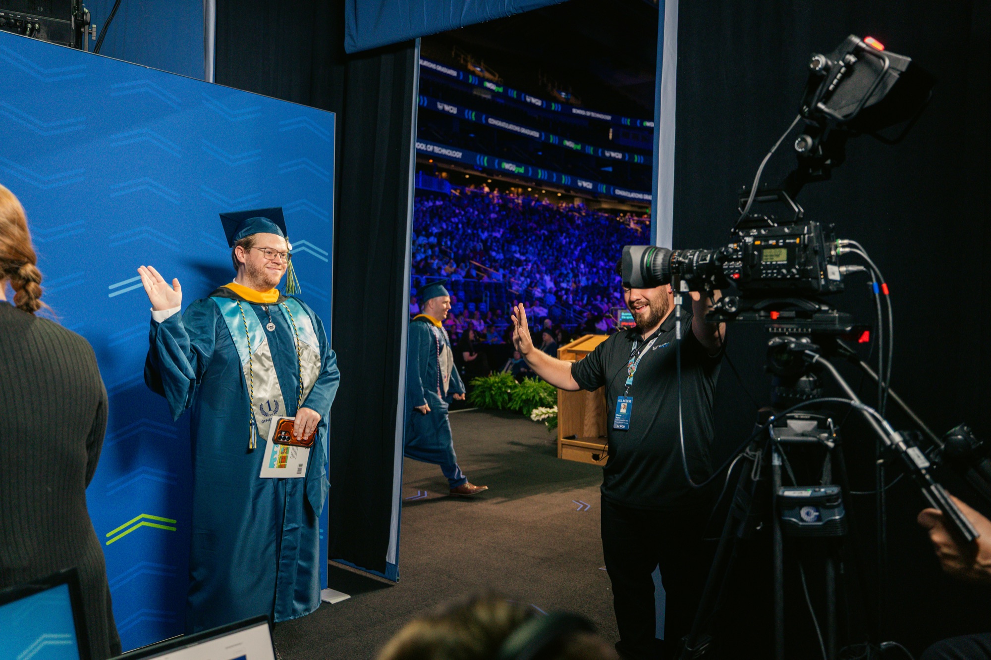 Camera operator capturing a graduate at the name display