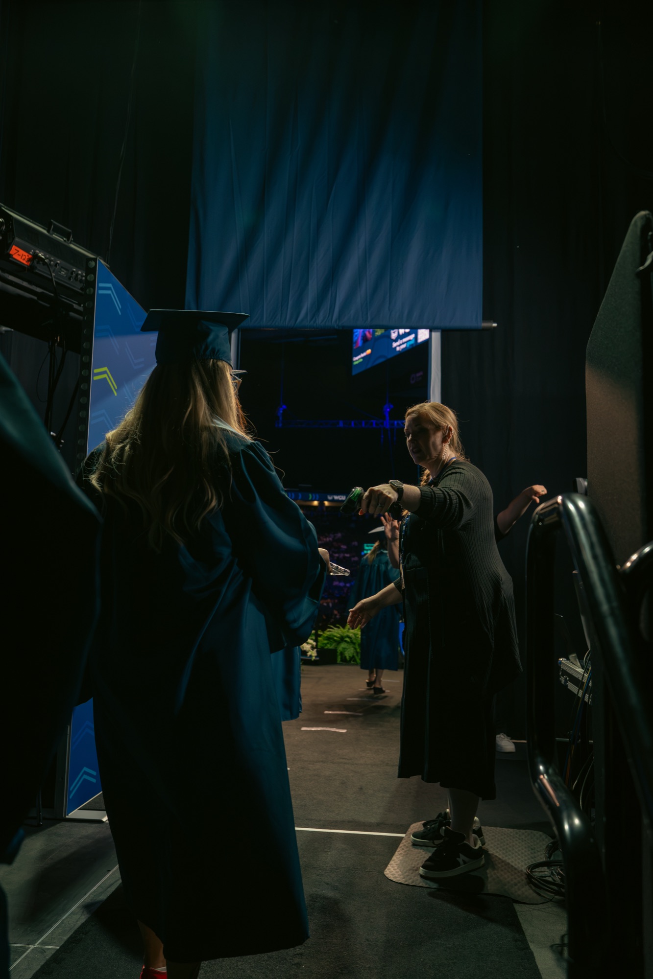 Staff scanning a graduate's QR code backstage before the stage entrance