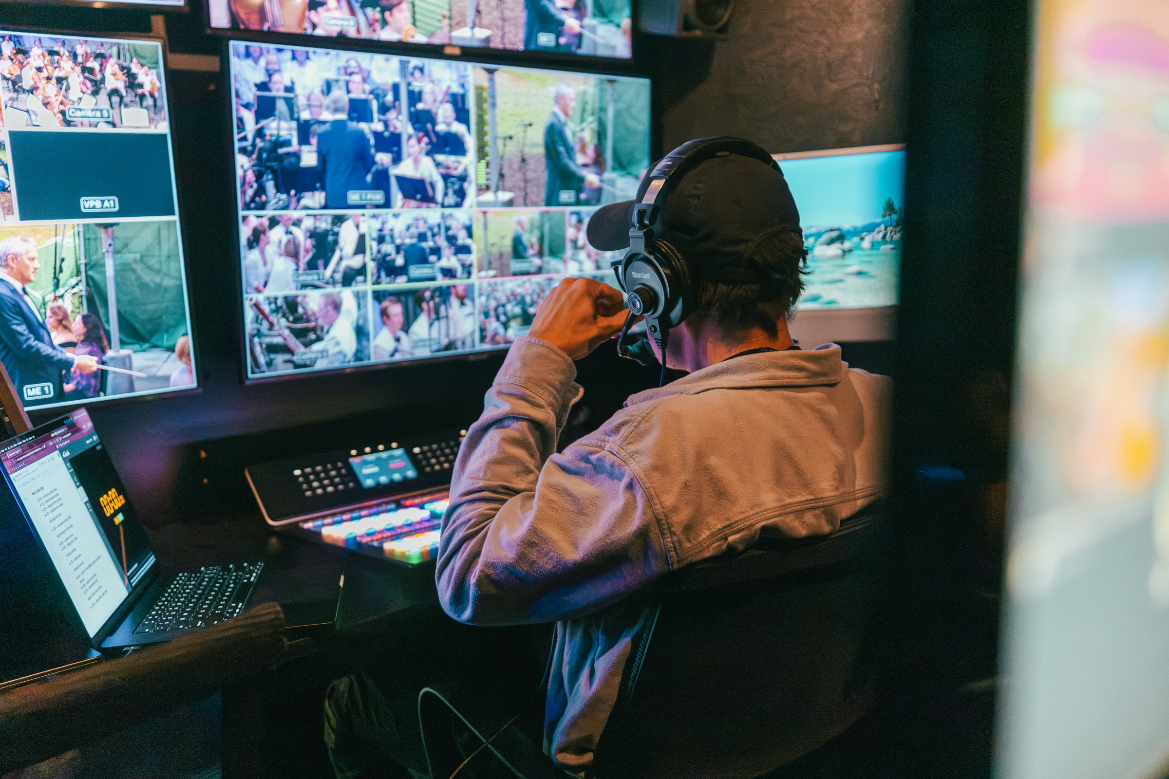 Operator on headset cutting cameras at the switcher inside the small trailer