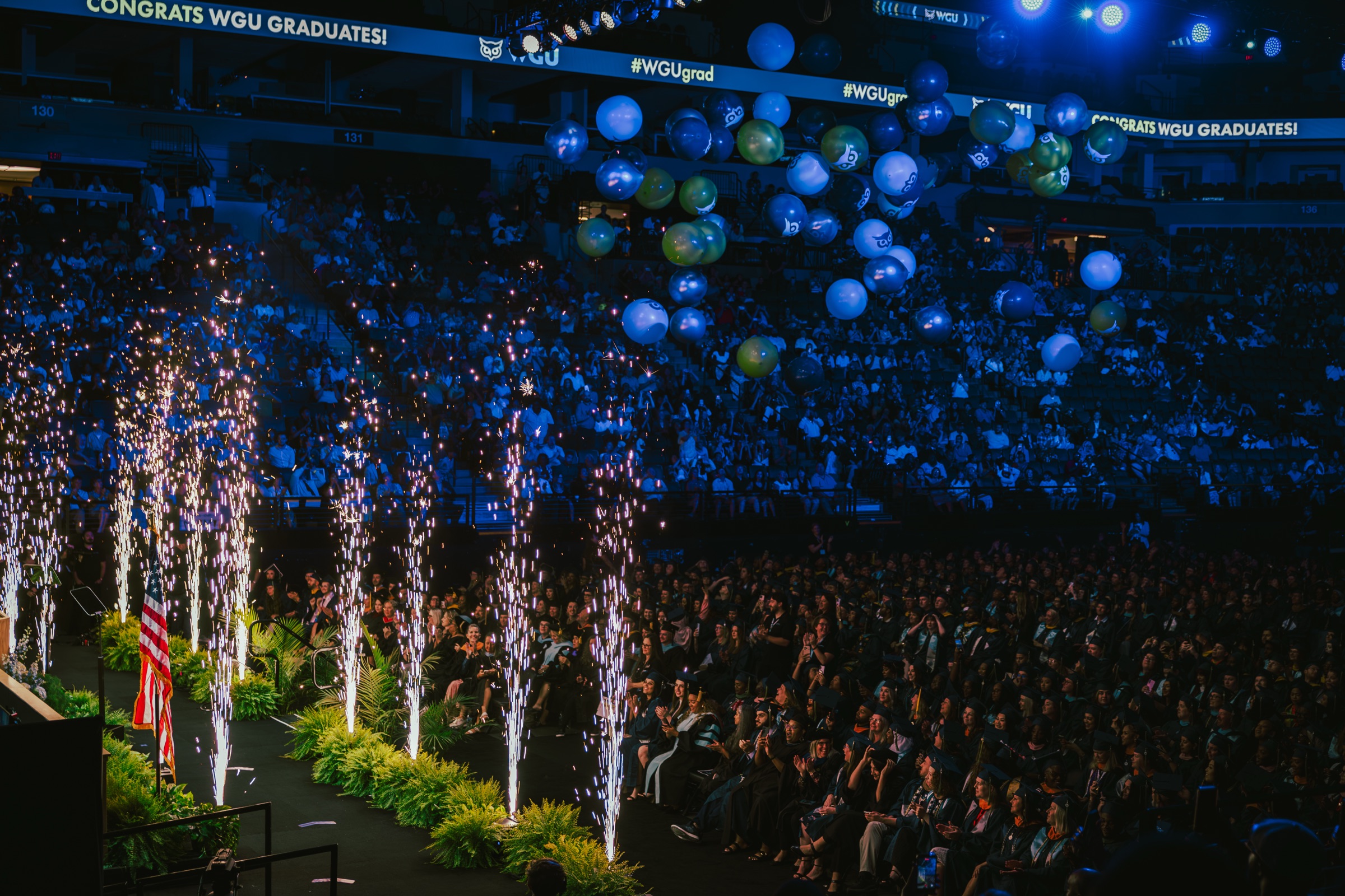 Pyrotechnic fountains firing beside the graduate floor as balloons drop over the arena