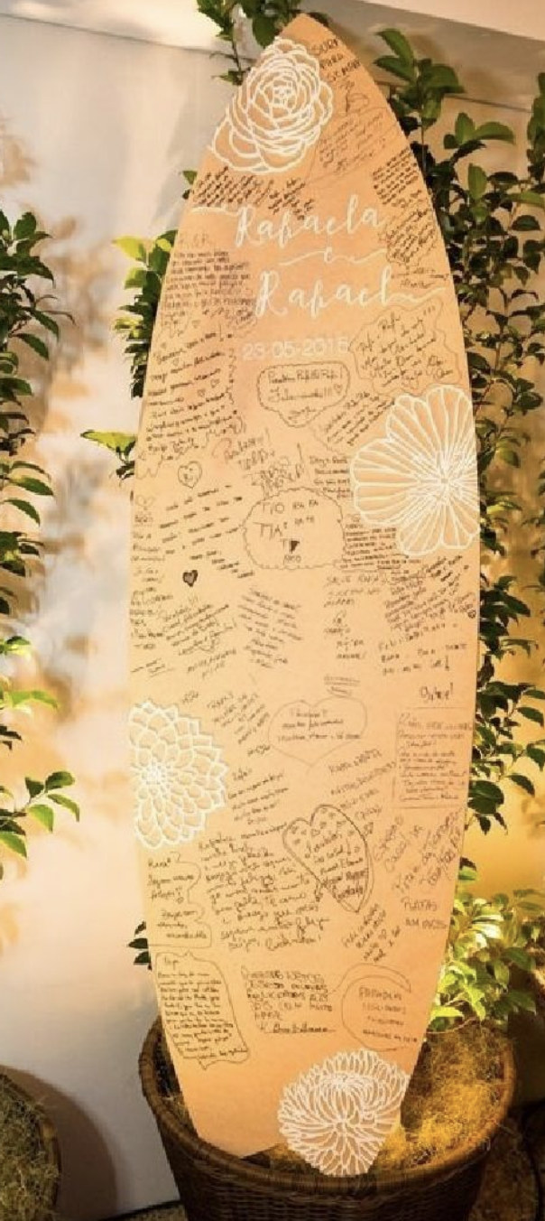 Kraft surfboard guestbook covered in handwritten messages with white floral illustrations