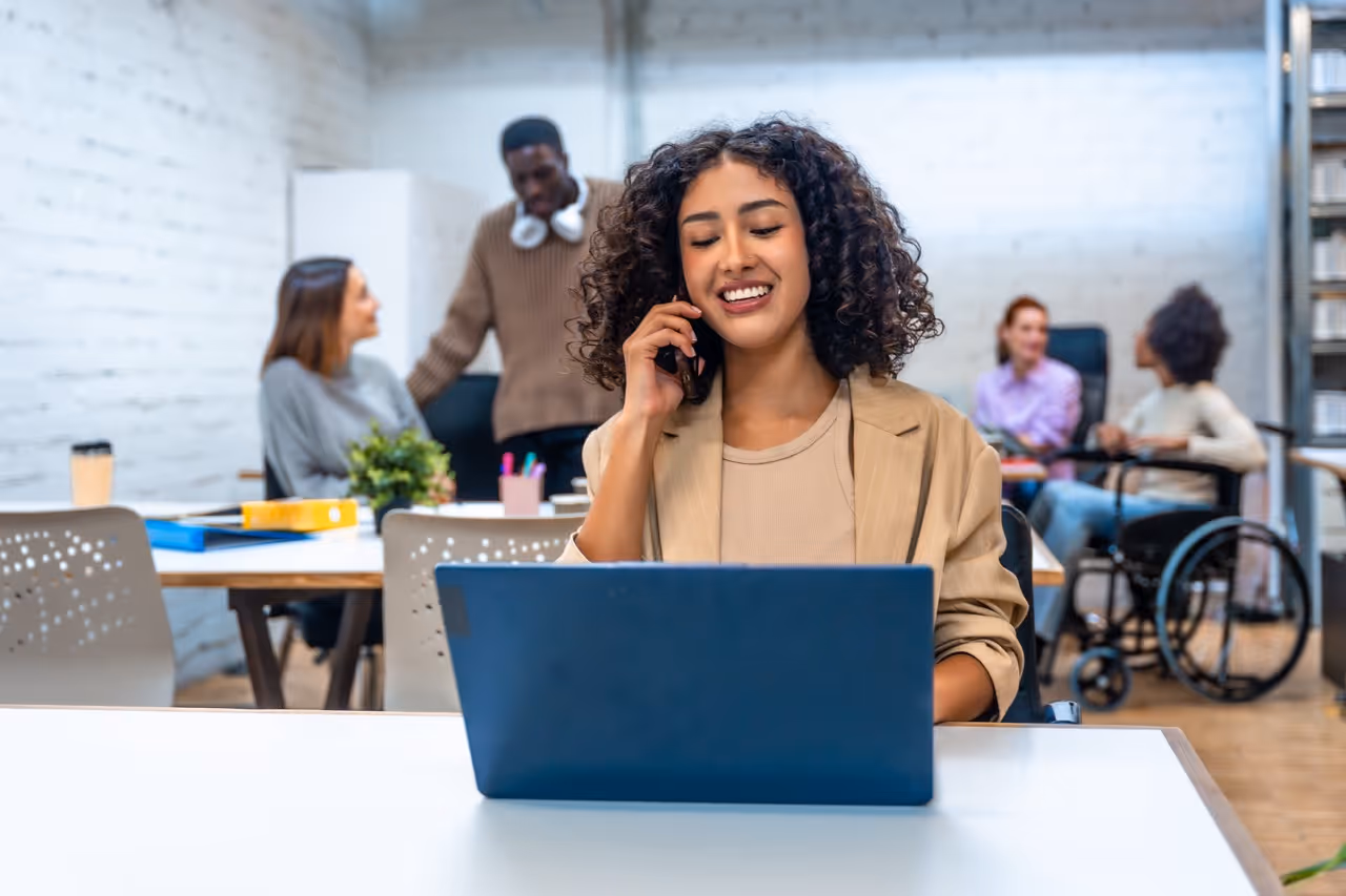 Recruiter on a call at her laptop in a busy open office