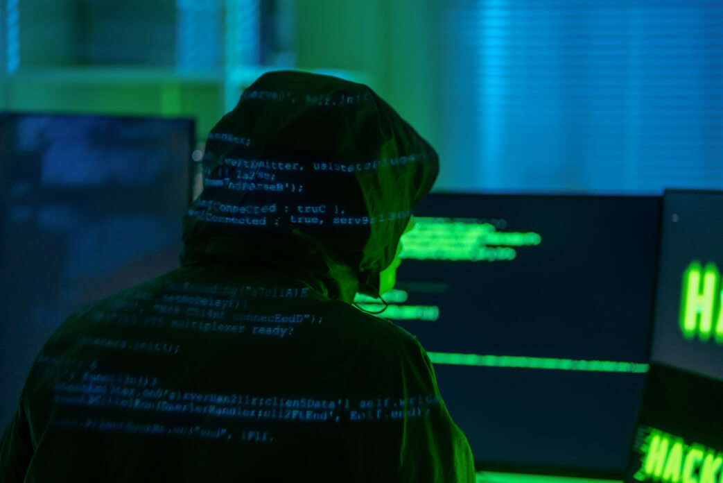 Person with hoodie typing on computer with strange symbols