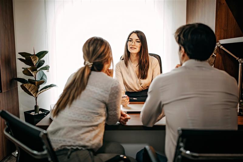 couple speaking to person behind desk