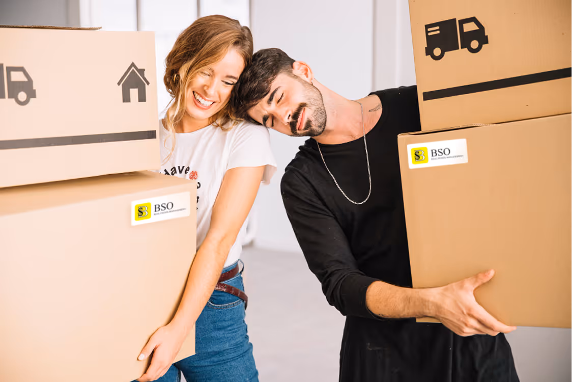 Smiling couple carrying BSO-labeled boxes, symbolizing a smooth move-in experience for tenants.