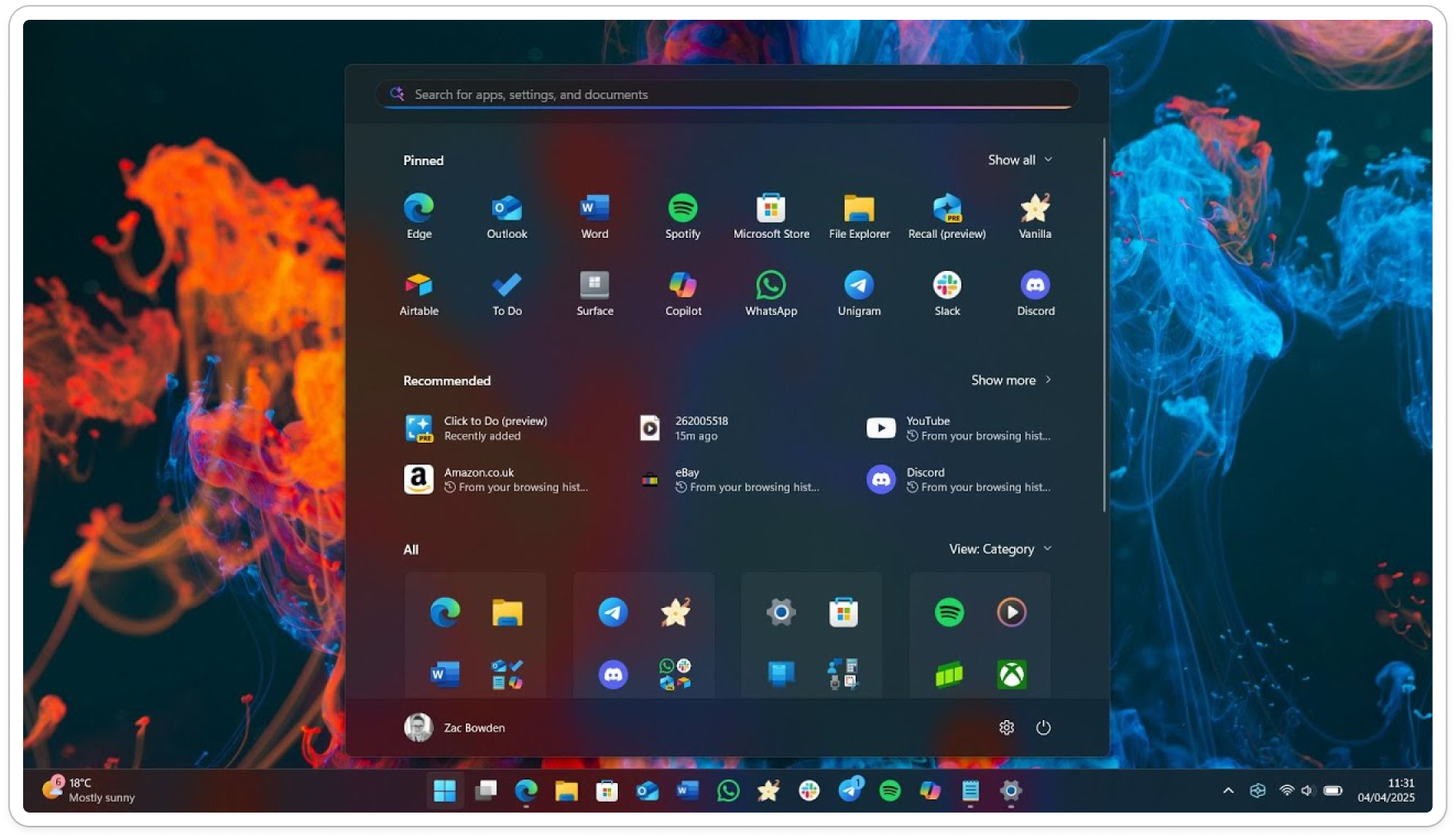 Windows 11 Start menu showing pinned apps like Outlook, Word, Spotify, and recommended apps, with a vibrant, colorful background of fluid patterns.