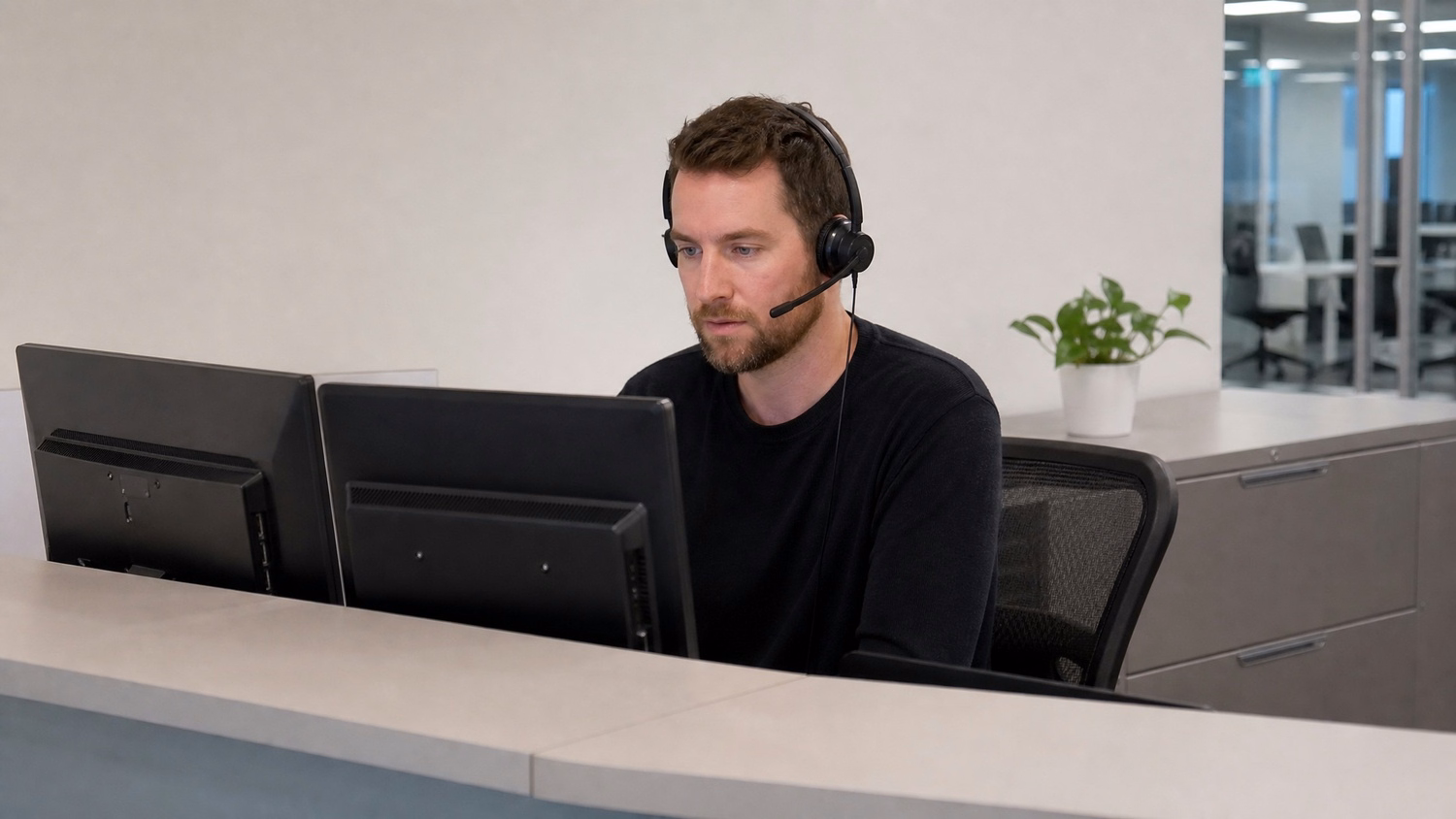 HELP DESK COUNTER, one person at a help desk counter with headset and two m