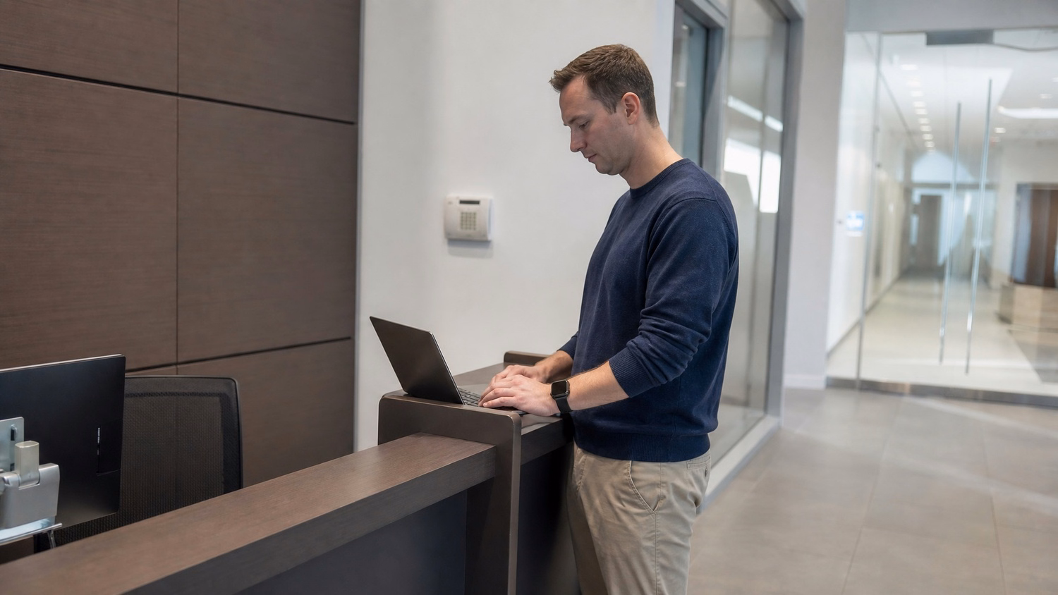 RECEPTION AREA, one person standing at a front reception desk in a modern o