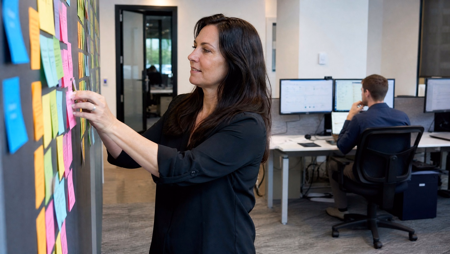 Woman organizing colorful sticky notes on wall 53 chars