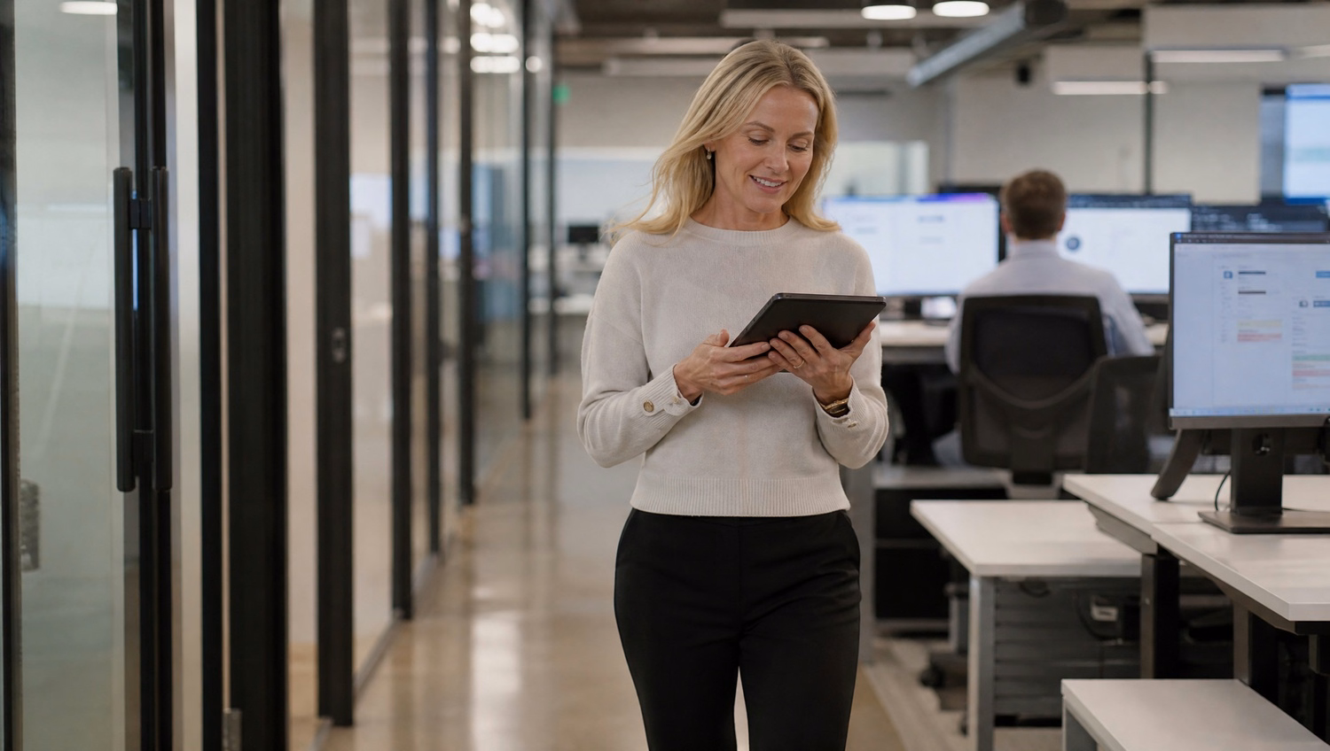 Woman with tablet walks through office corridor reviewing document 70