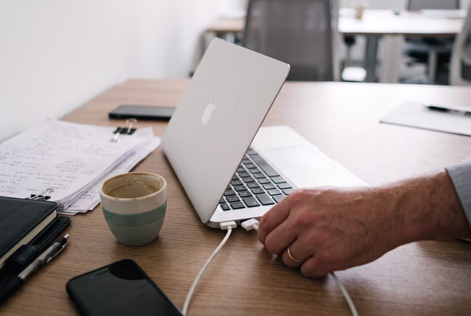 Hand unplugging laptop on cluttered office desk