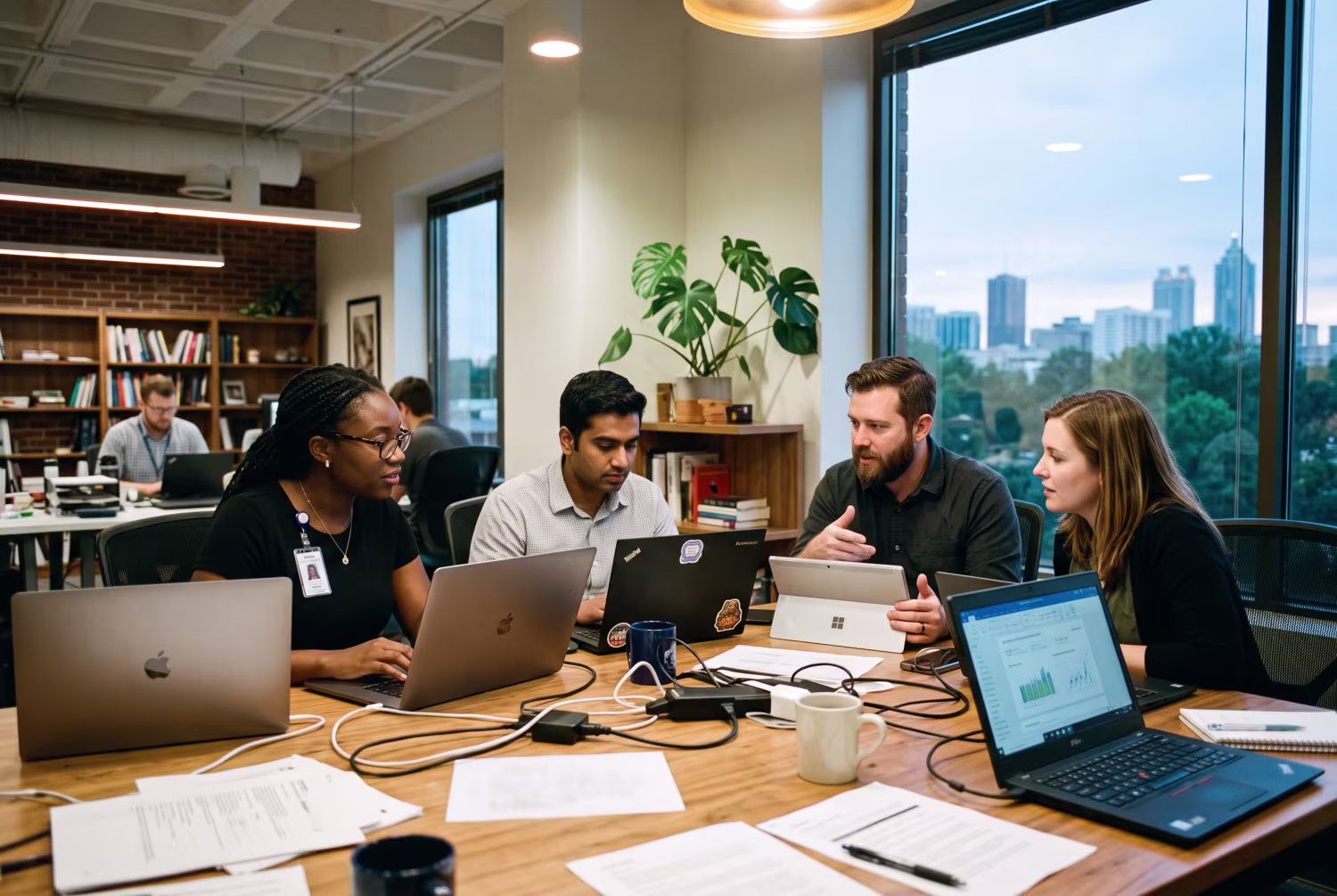 IT professionals working with both MacBooks and Windows laptops in mixed lighting