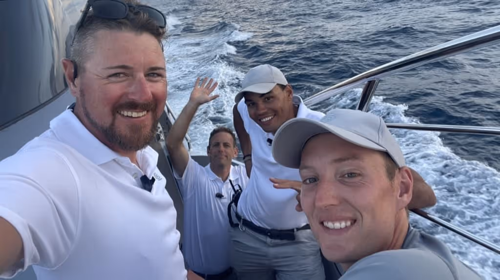 Four Relief Crew volunteers taking a group selfie on a yacht, smiling as they sail on the ocean.