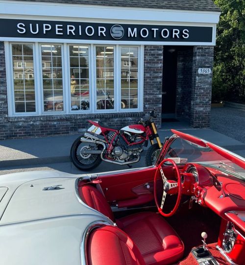 Red interior of a car next to a motorcycle in front of Superior Motors.