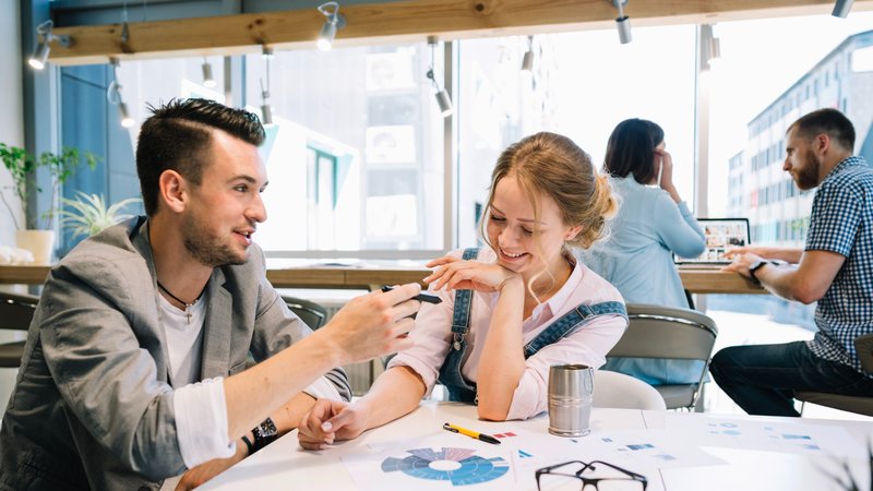 Two teammates laughing together in a modern office