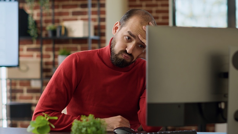 Man looking overwhelmed and stressed, surrounded by redundant and repetitive tasks piling up around him