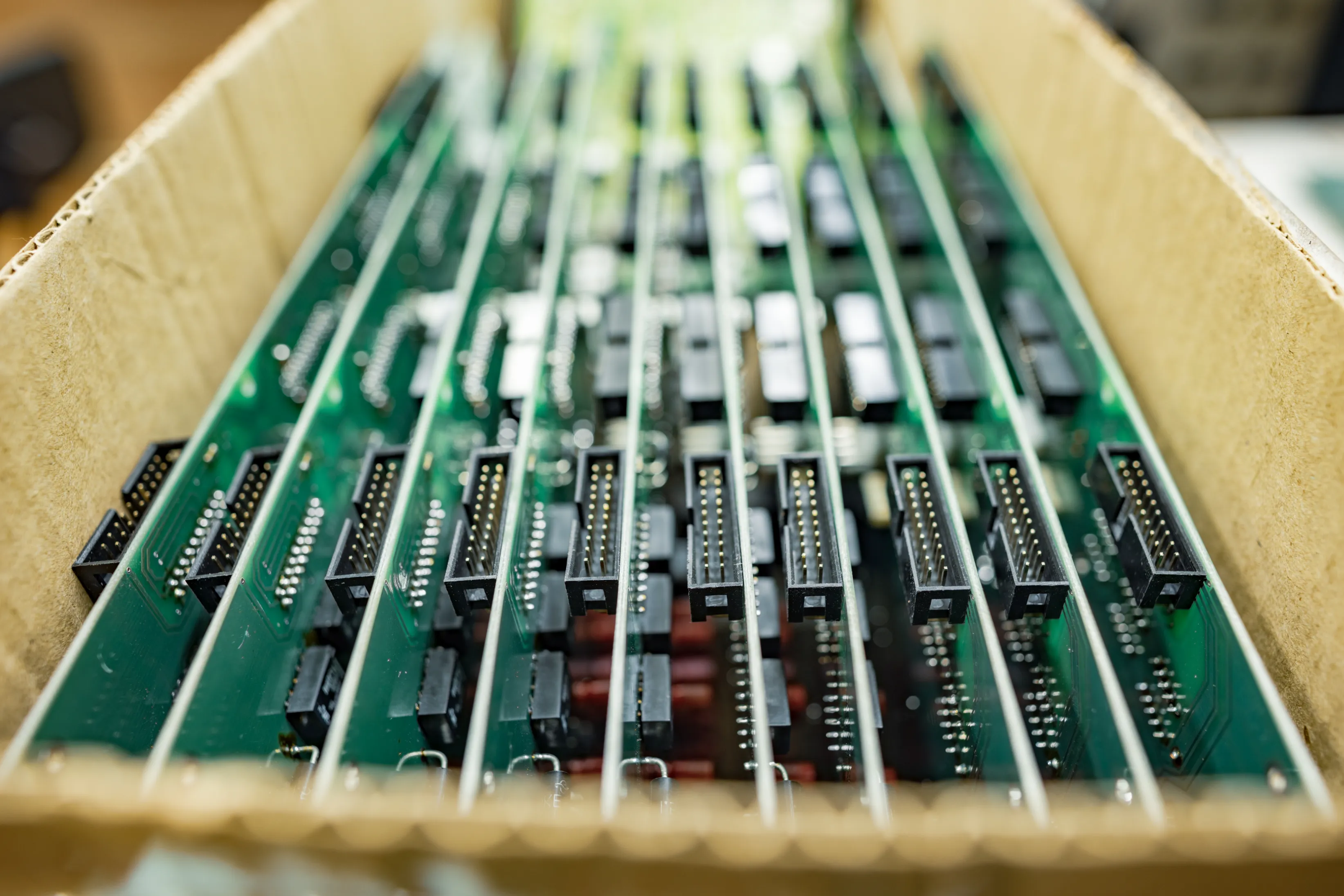 A box of fully assembled PCBs lined up, each with connectors ready for the next stage of processing. This image represents consigned PCB assembly, where components provided by the client are assembled onto circuit boards with accuracy and efficiency.