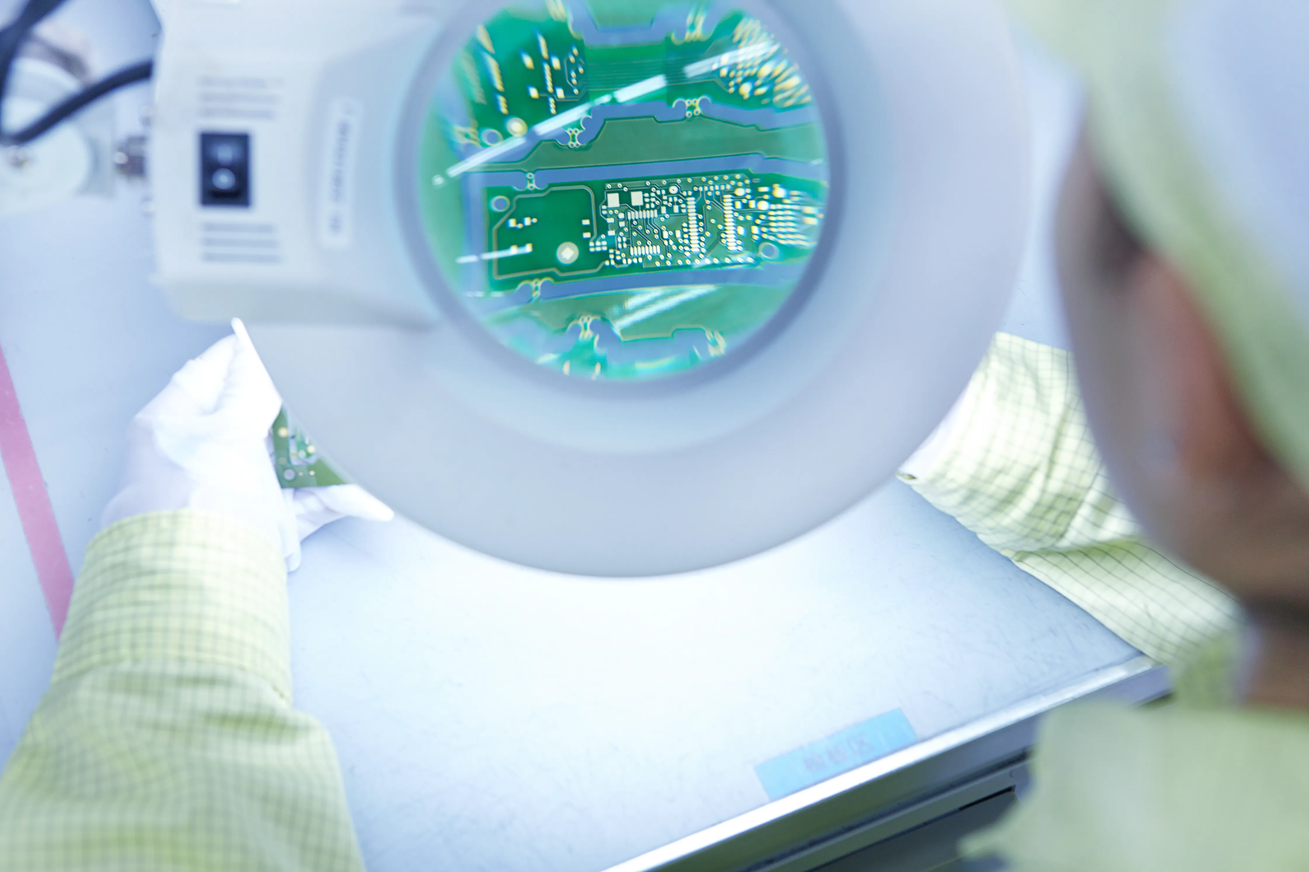 A technician carefully examining a PCB under a magnifying lens during functional testing. This process ensures that the assembled board functions correctly and meets all design and performance specifications before it moves to the next phase.