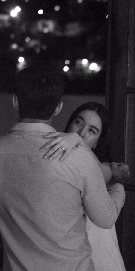 Arantxa y Eugenio se abrazan en un balcón del hotel Hércules en Querétaro. La toma enfoca la mano de Arantxa con su anillo de compromiso.