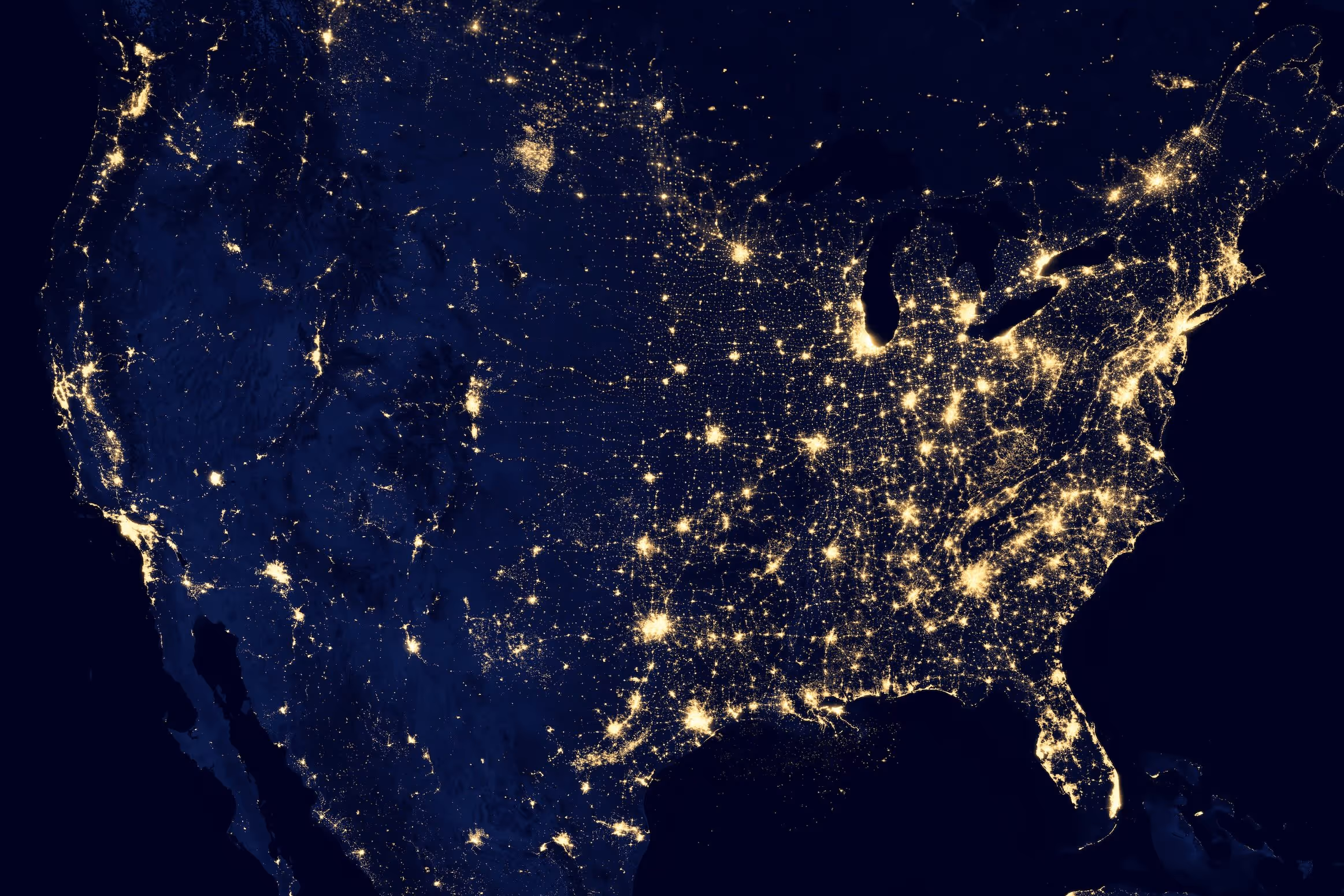 Satellite image of the United States at night showing city lights indicating population centers and urban areas.