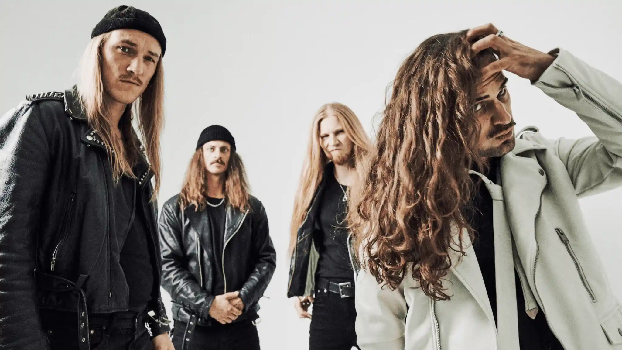 Four men with long hair wearing leather jackets and serious expressions against a plain light background. band: DUST BOLT