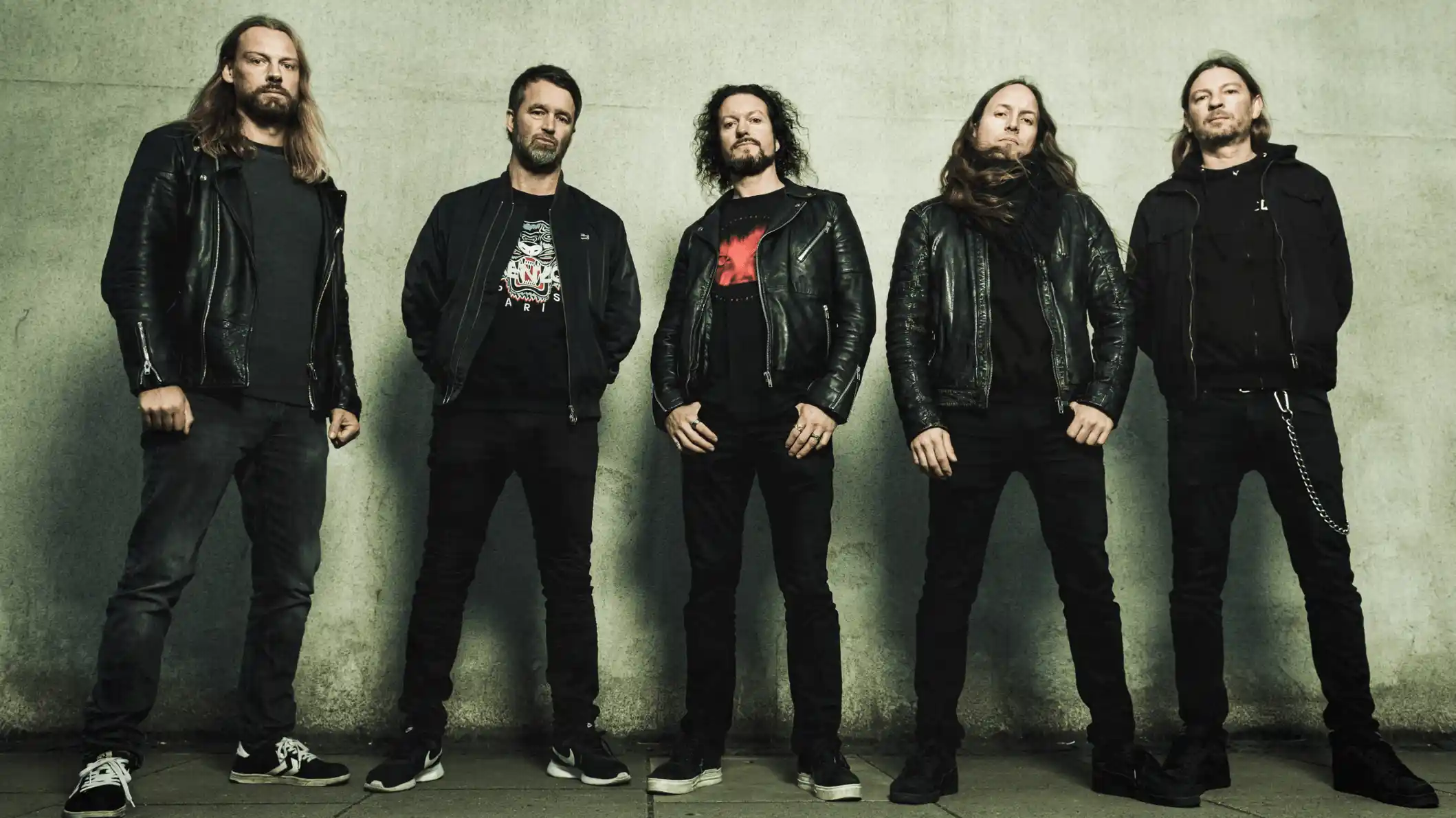 Five men standing against a wall wearing black jackets and dark pants, posing for a group photo. BAND: ILLDISPOSED