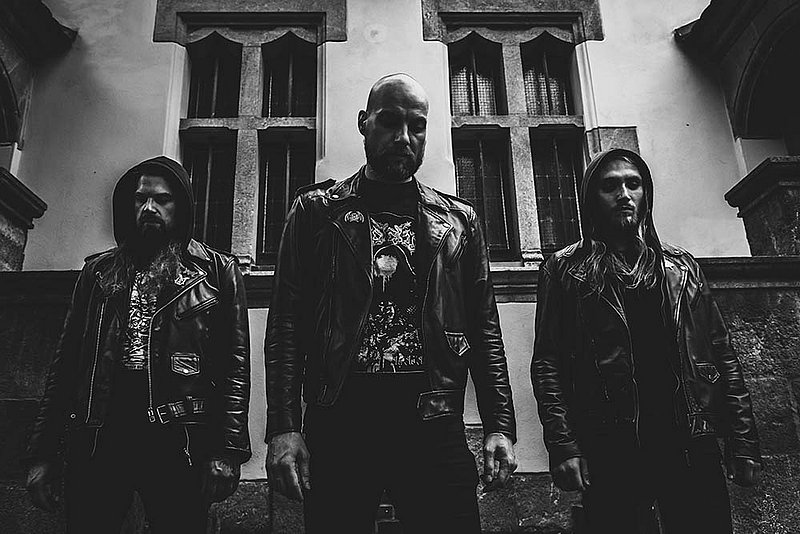 Five men with serious expressions standing against a graffiti-covered brick wall, wearing band and metal-themed clothing. Band: ENDSEEKER