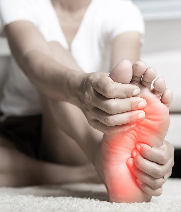 Peripheral neuropathy concept: A patient is holding their foot, which is colored red, indicating pain and inflammation.
