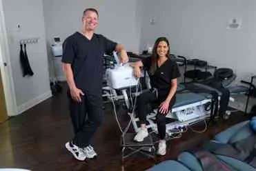Dr. Scott and Dr. Dana LeBlanc with a spinal decompression table at LeBlanc Spine Center.