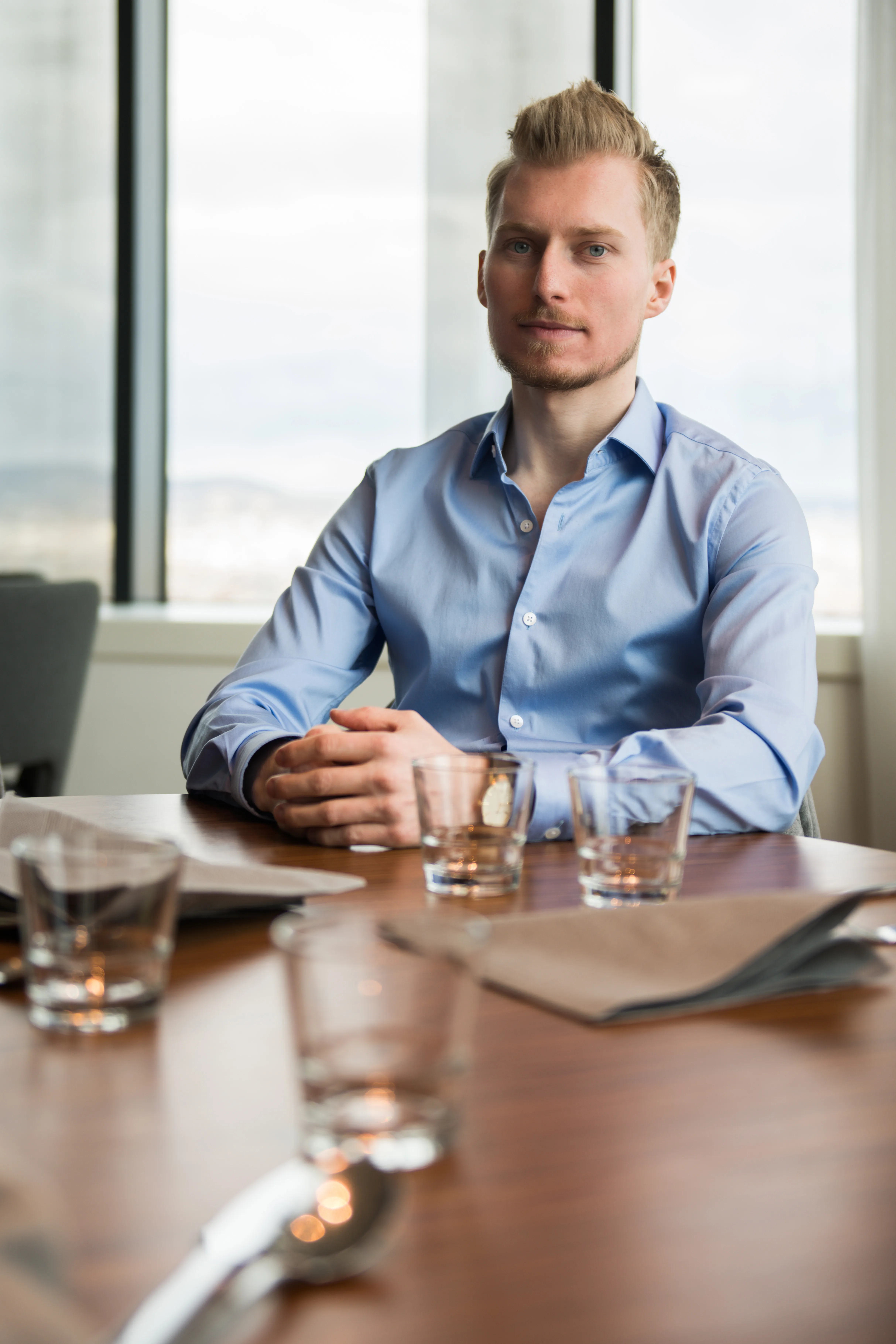 James Blond ist sitzend am Tisch abgebildet im Hemd.