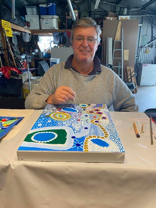 Kevin smiling at the camera while he paints