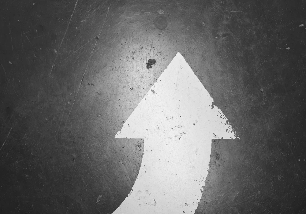 Flecha blanca pintada en el suelo de parking donde se cargan coches eléctricos.