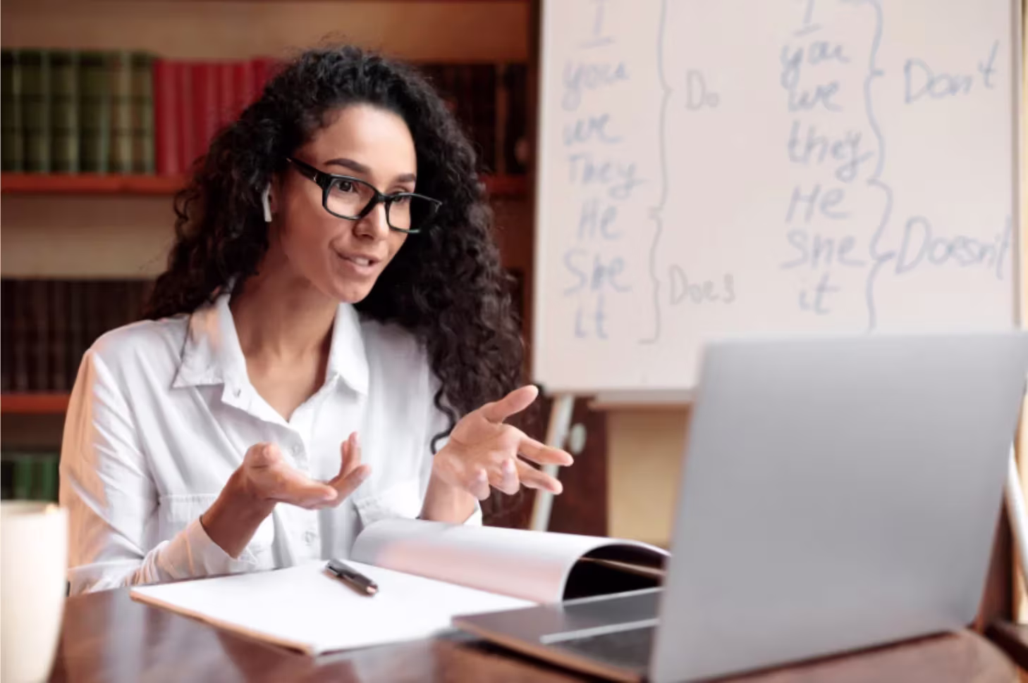 A woman talking on a meeting in front of her laptop.