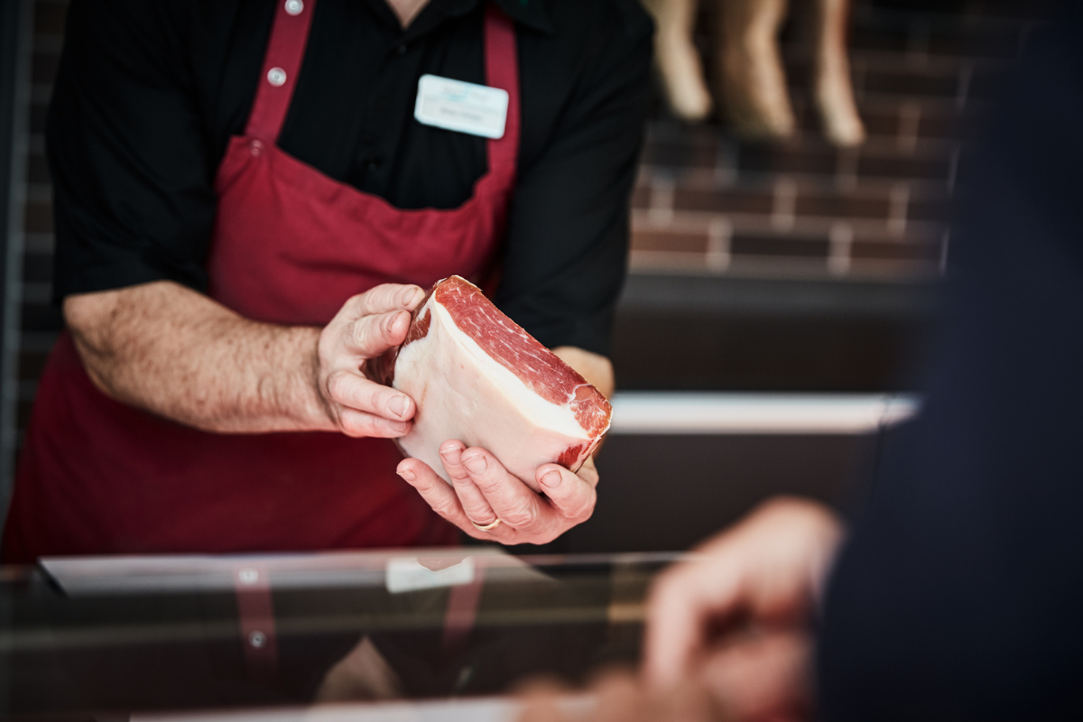 Butcher handing organic meat to customer