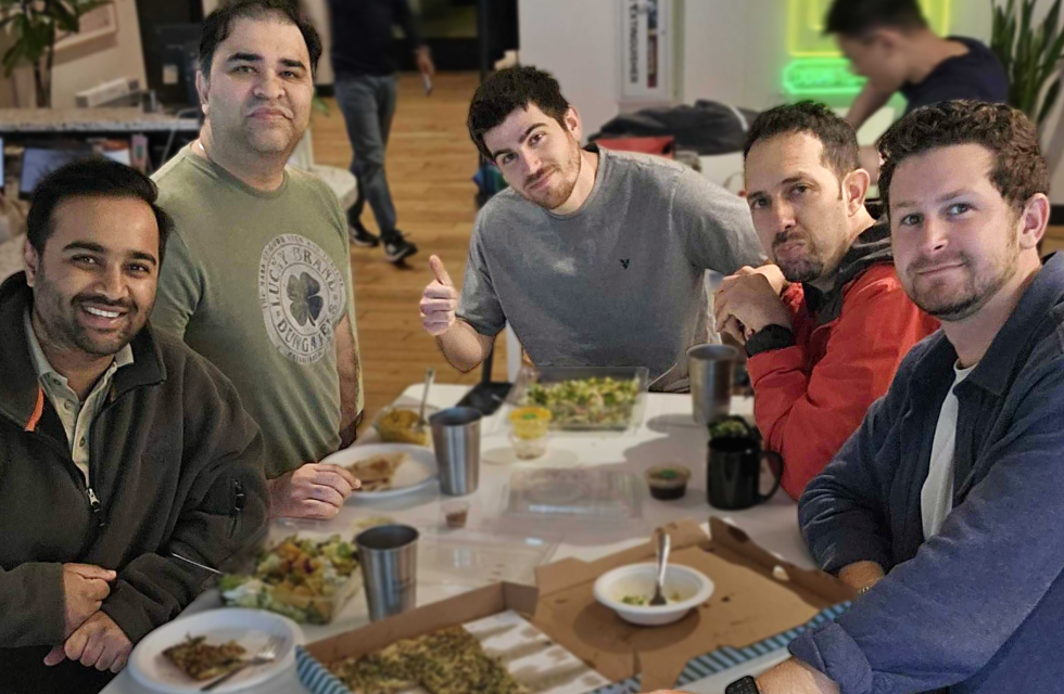 Five Opsin team members sitting around a table with food.
